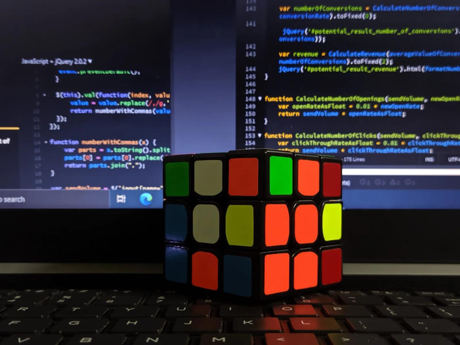 Cubo mágico diante de um monitor com código-fonte aberto num editor