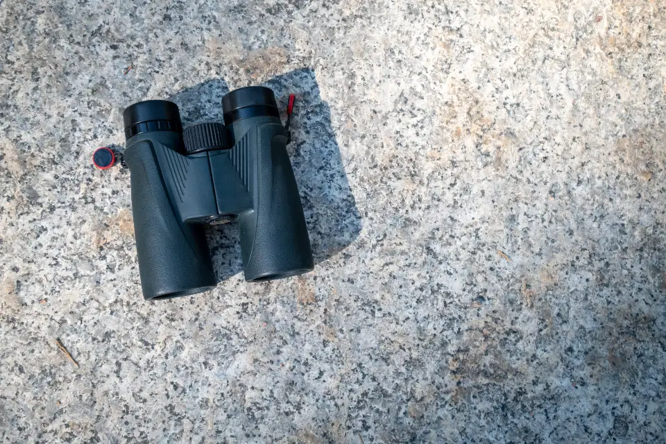 Binóculo preto sobre uma superfície de pedra, visto de cima