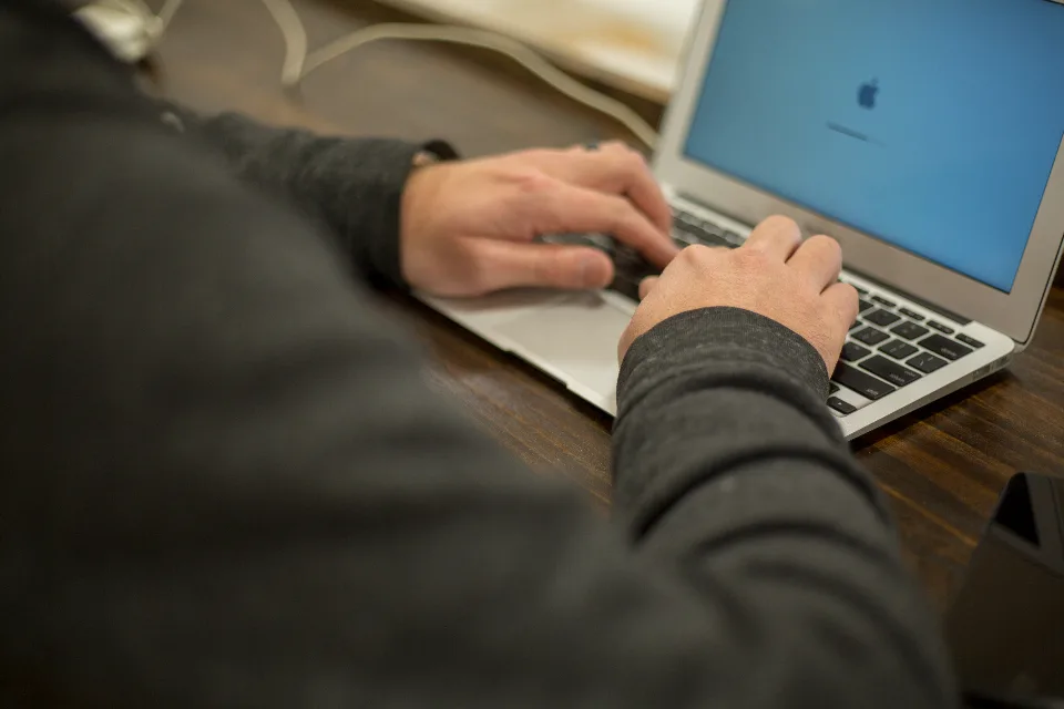 Pessoa trabalhando num notebook, com a mão sobre o teclado