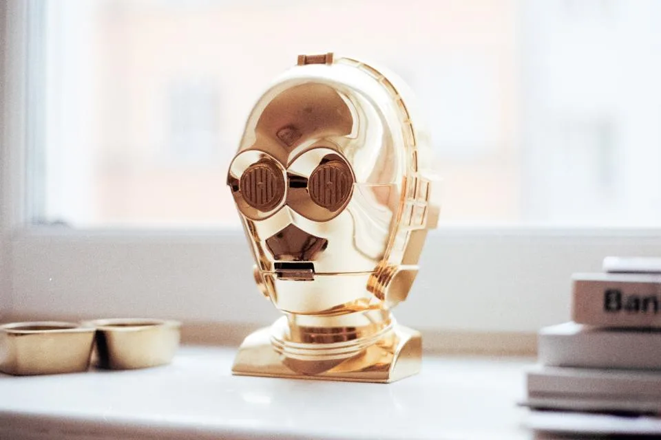 Robô dourado em miniatura sobre fundo escuro