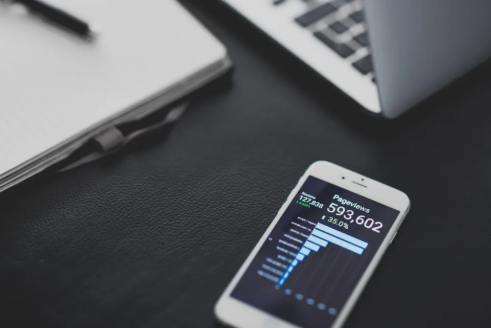 Celular sobre mesa escura exibindo um painel de análise com contagem de pageviews