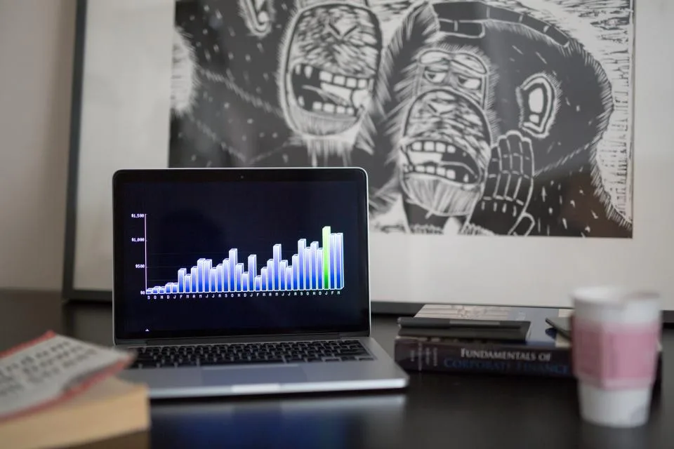 Notebook em ambiente escuro com gráficos coloridos de um painel de dados na tela
