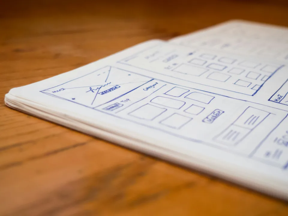 Caderno aberto com esboço de wireframe de telas desenhado à mão