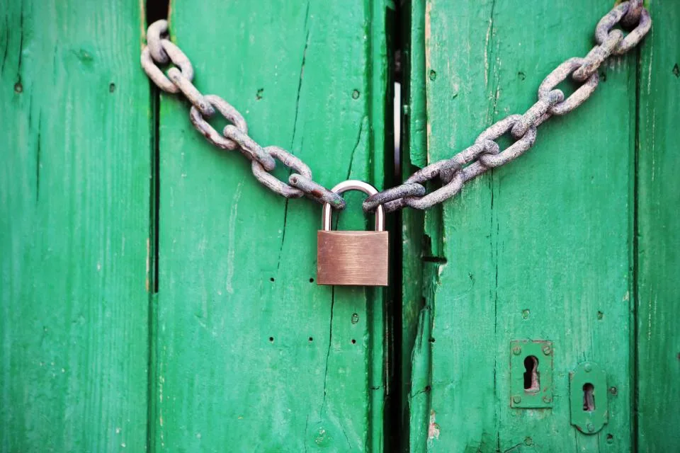 Cadeado e corrente prendendo uma porta de madeira verde