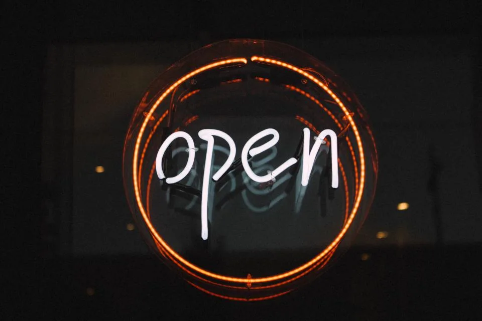 Letreiro em neon aceso na fachada de um estabelecimento à noite