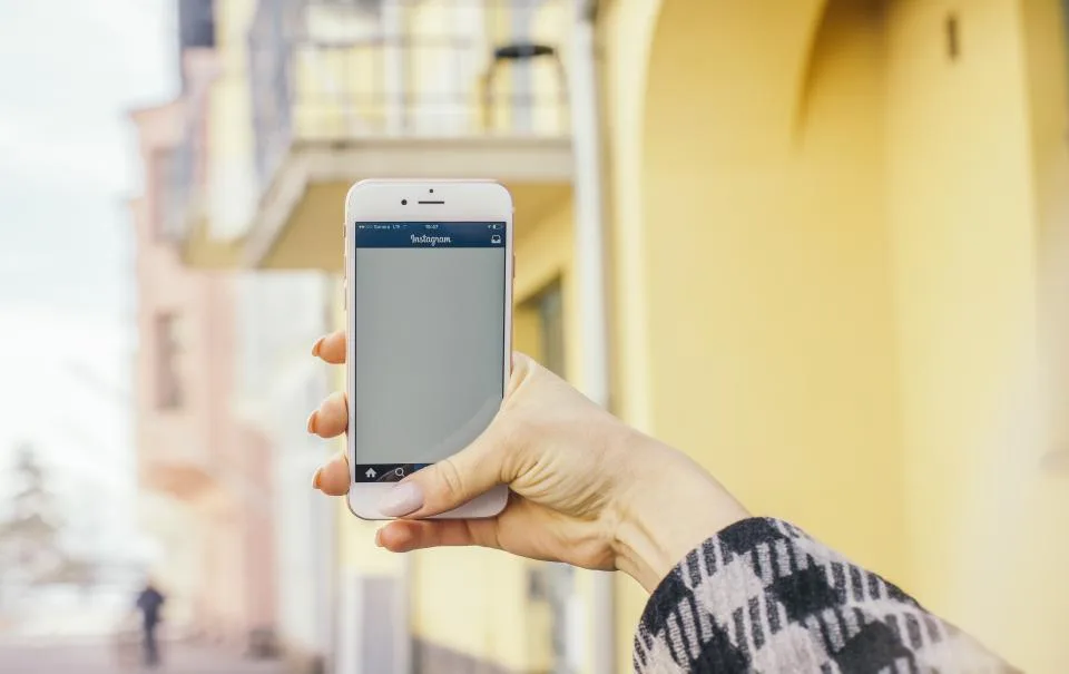 Mão segurando smartphone com o Instagram aberto