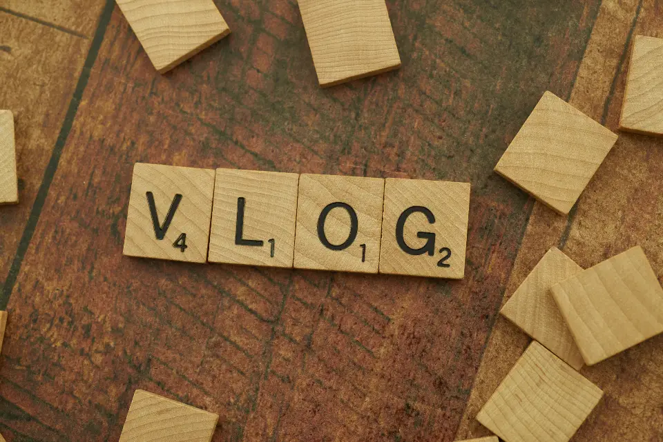 Peças de jogo de letras formando a palavra vlog sobre a mesa