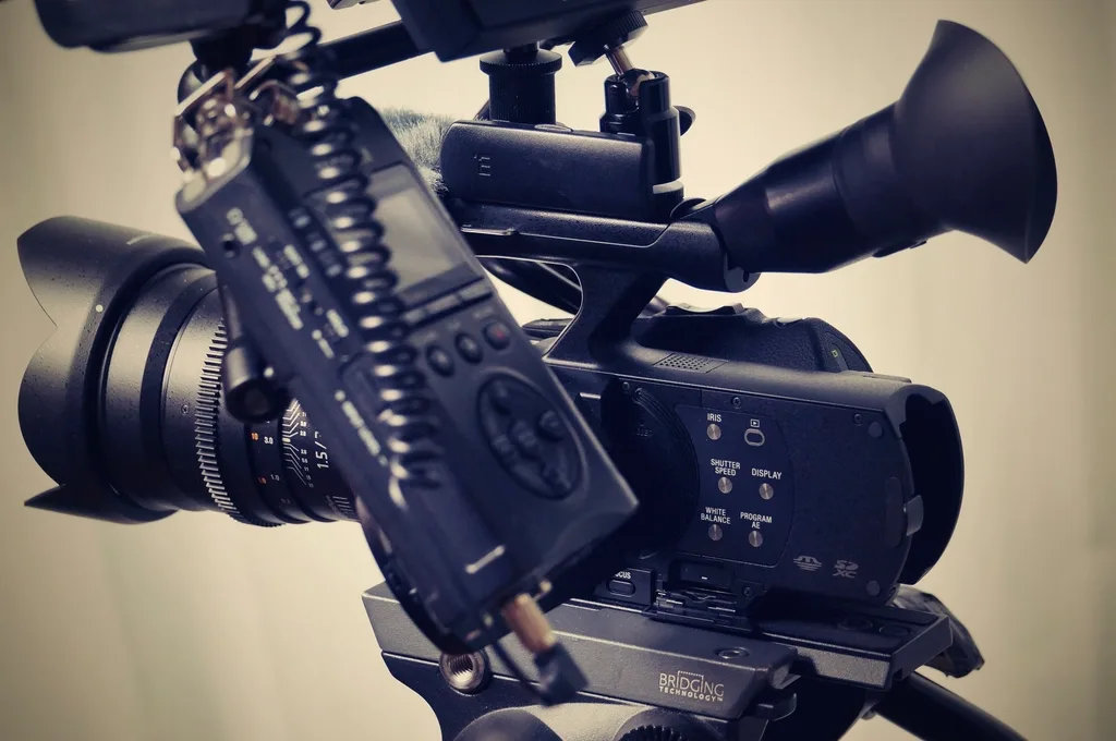 Câmera de vídeo profissional montada em tripé, com microfone direcional e monitor acoplados, pronta para captação