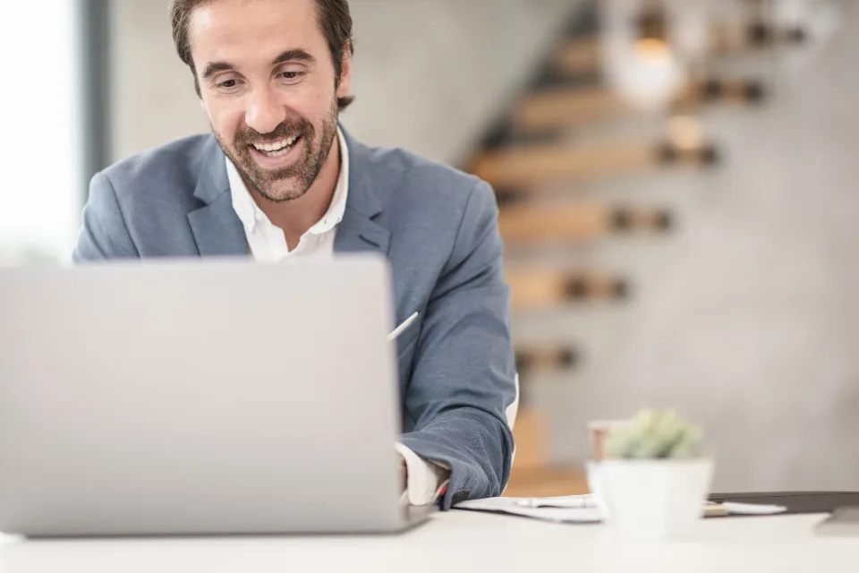 Homem sorrindo numa videochamada pelo notebook